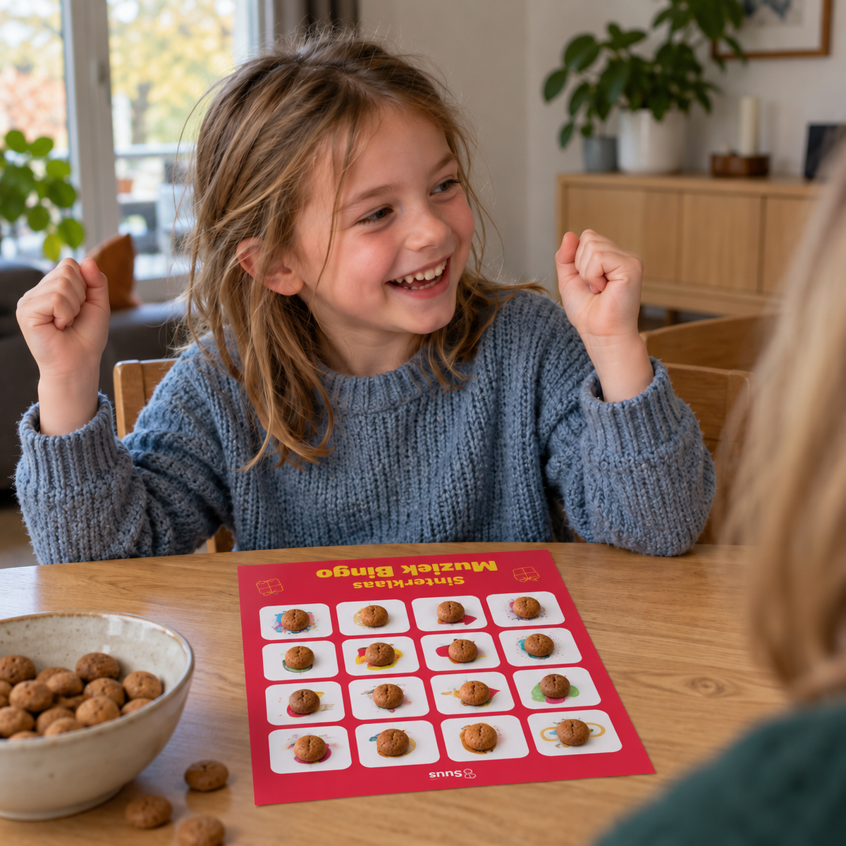 Een meisje juicht omdat haar muziekbingo-kaart vol ligt met pepernoten